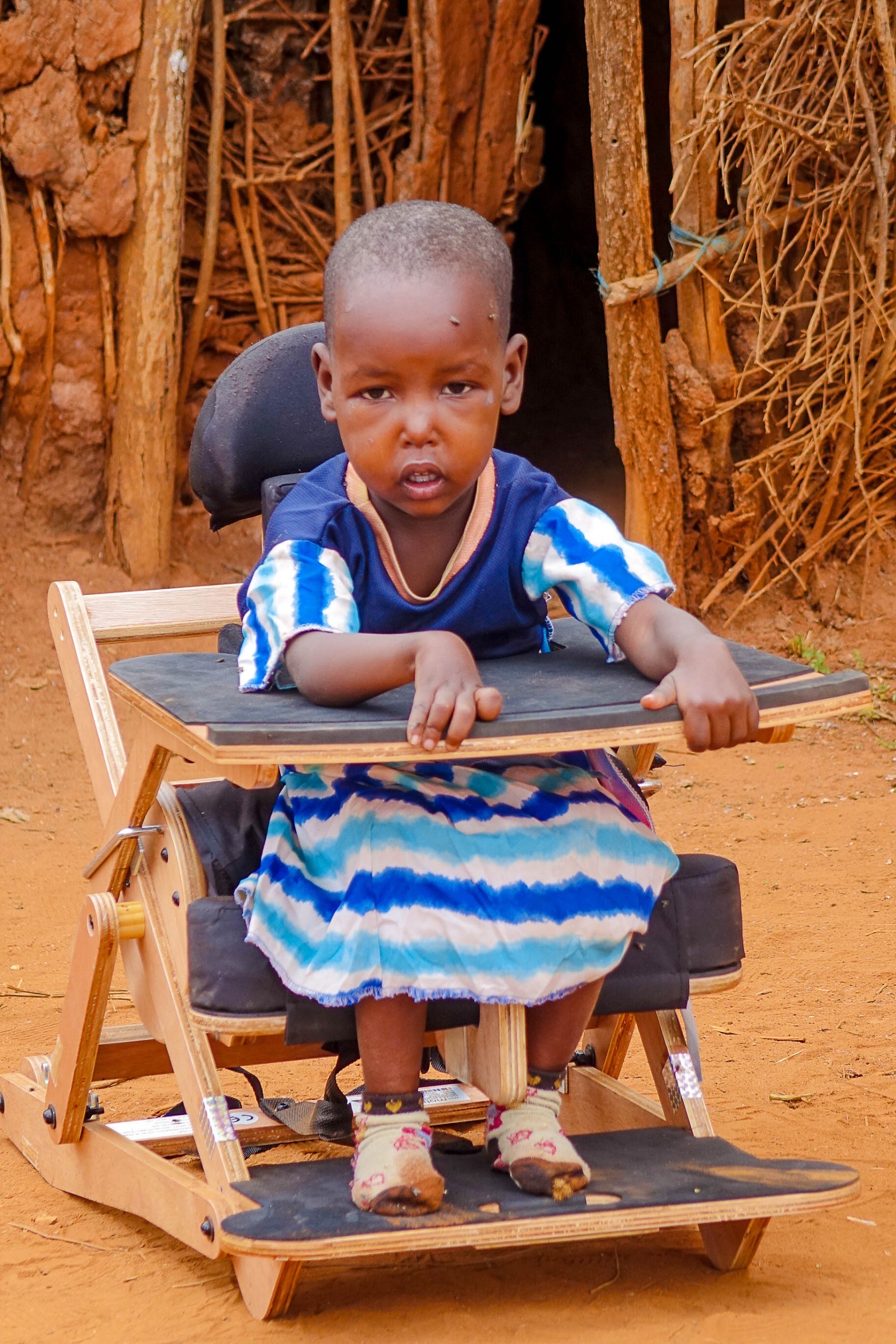 En liten flicka i rullstol utomhus i Kenya