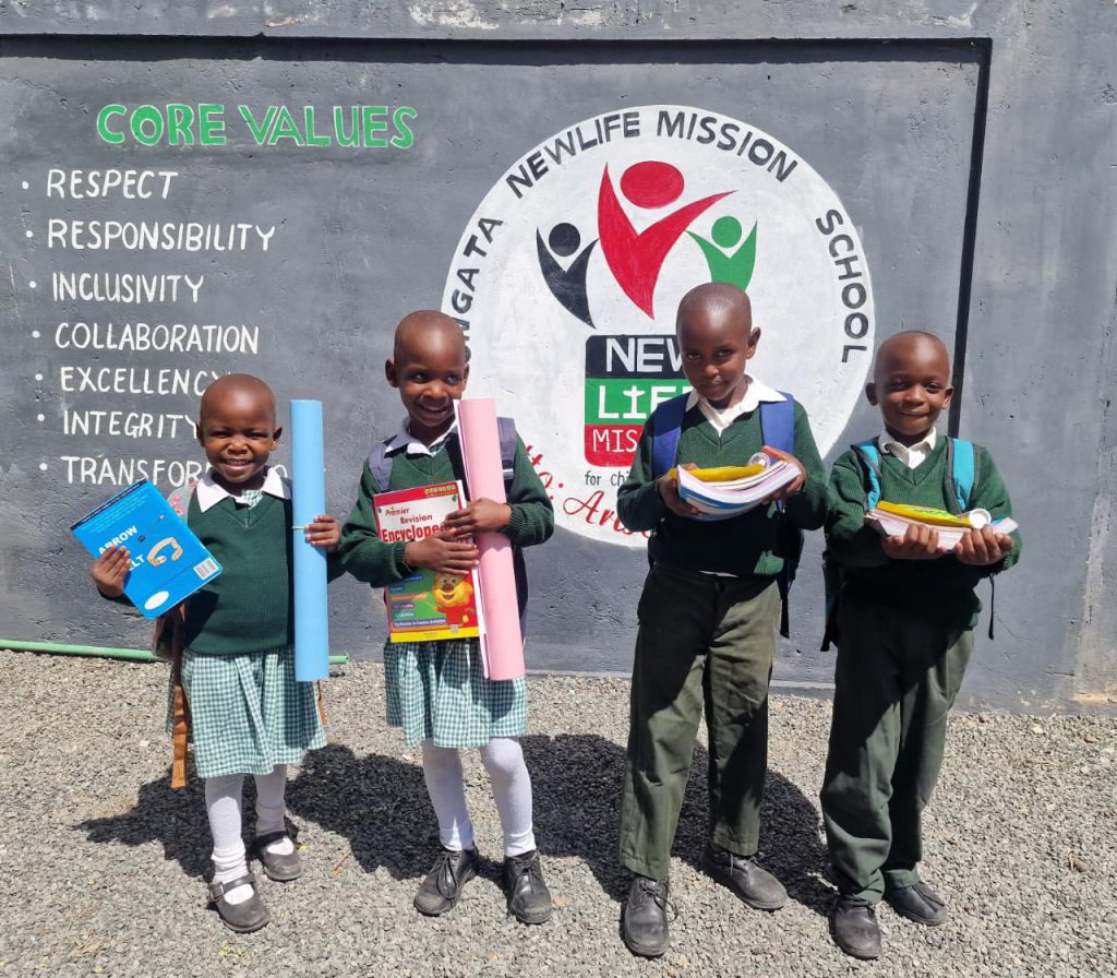 Förskolebarn står framför New Life Missions logga vid förskolan i Kenya